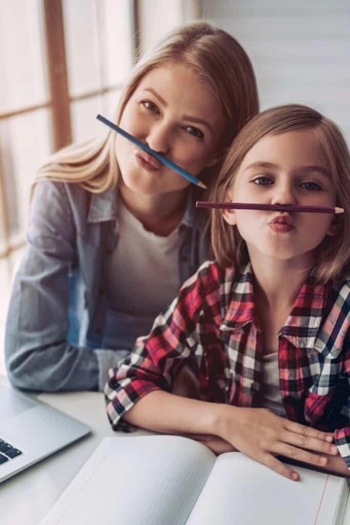 woman and little girl making silly faces while holding pencils between their lips and noses