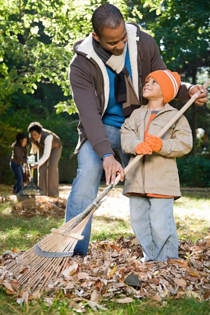 father and son raking leaves together