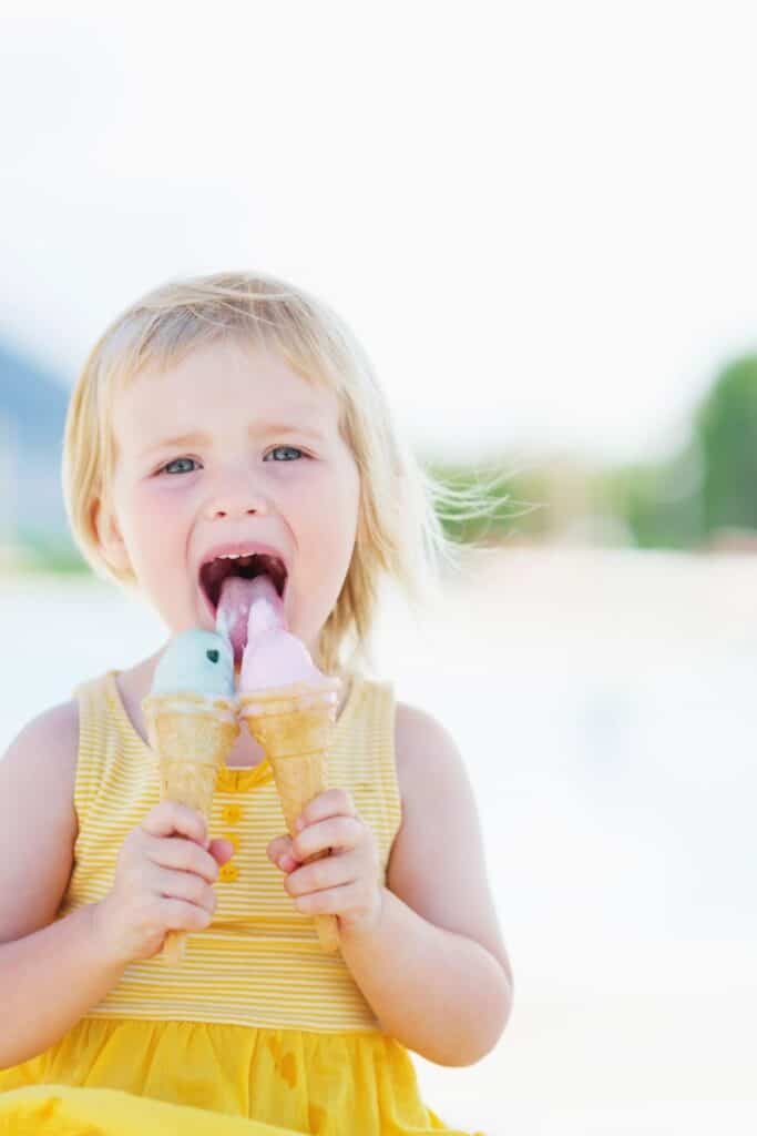 little girl eating two ice cream cones