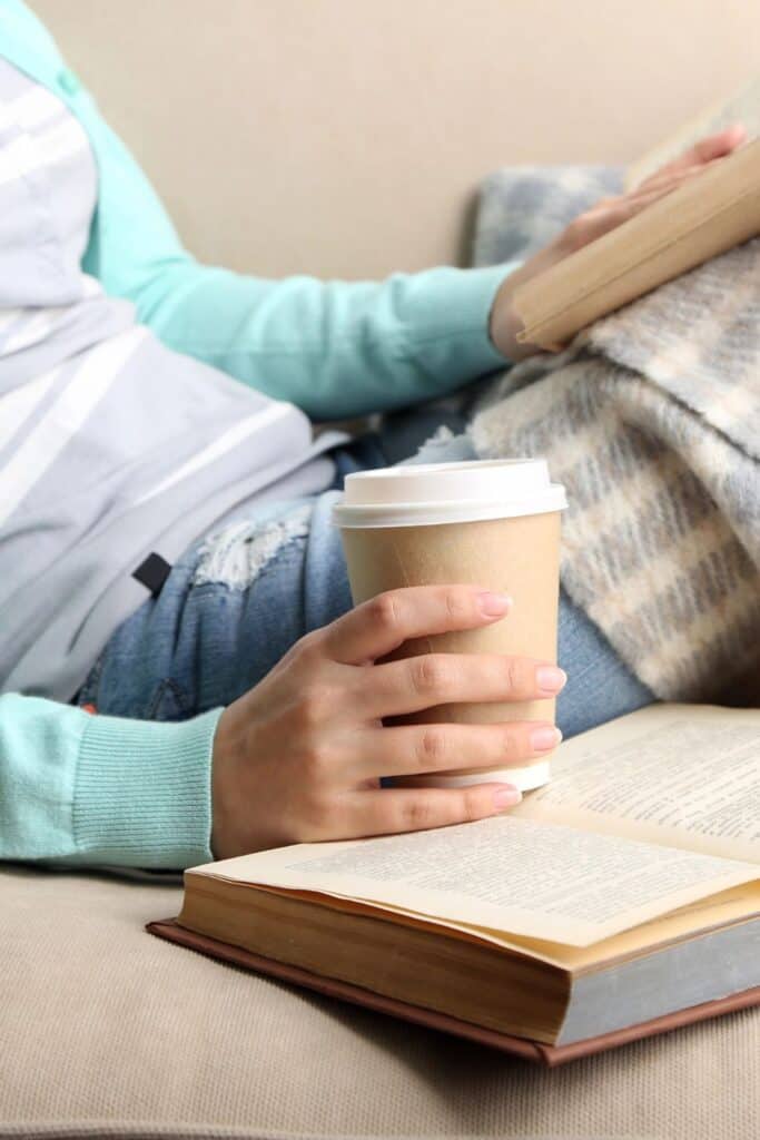 woman reading on a couch while drinking coffee