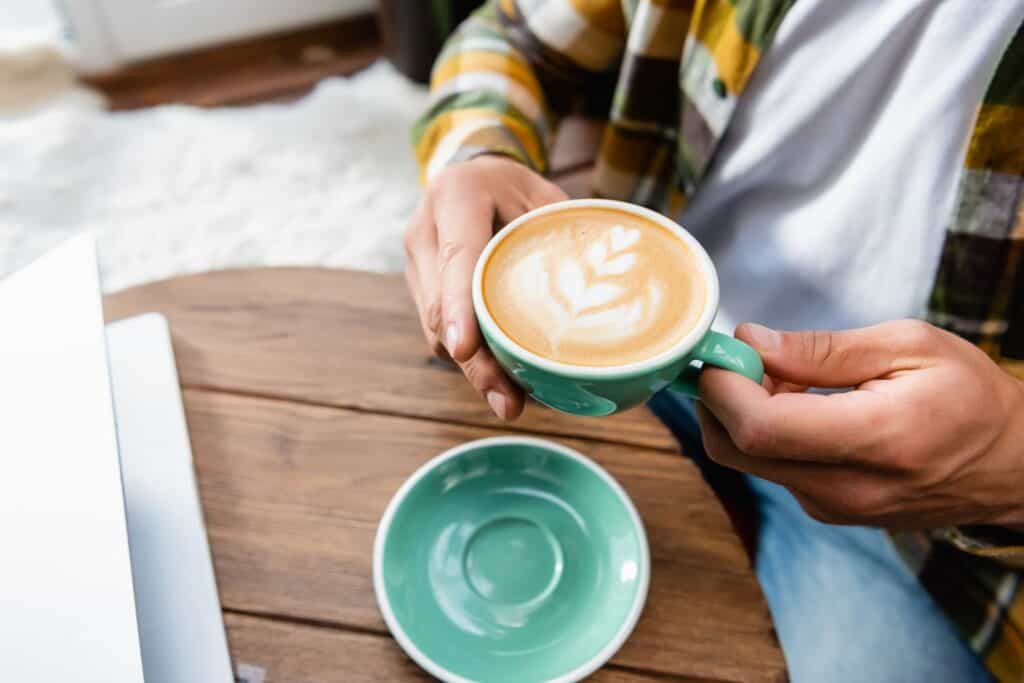 woman drinking a cup of coffee with a leaf displayed on top of the coffee