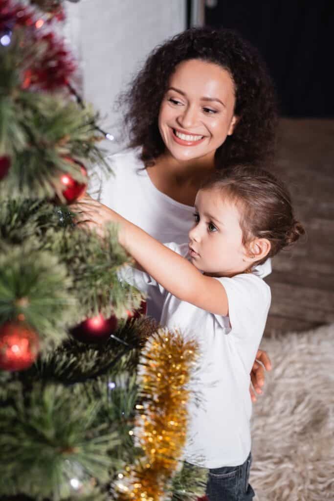 woman and little girl decorating a Christmas tree