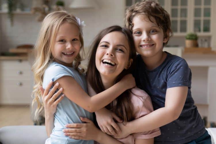 woman hugging her two children and smiling
