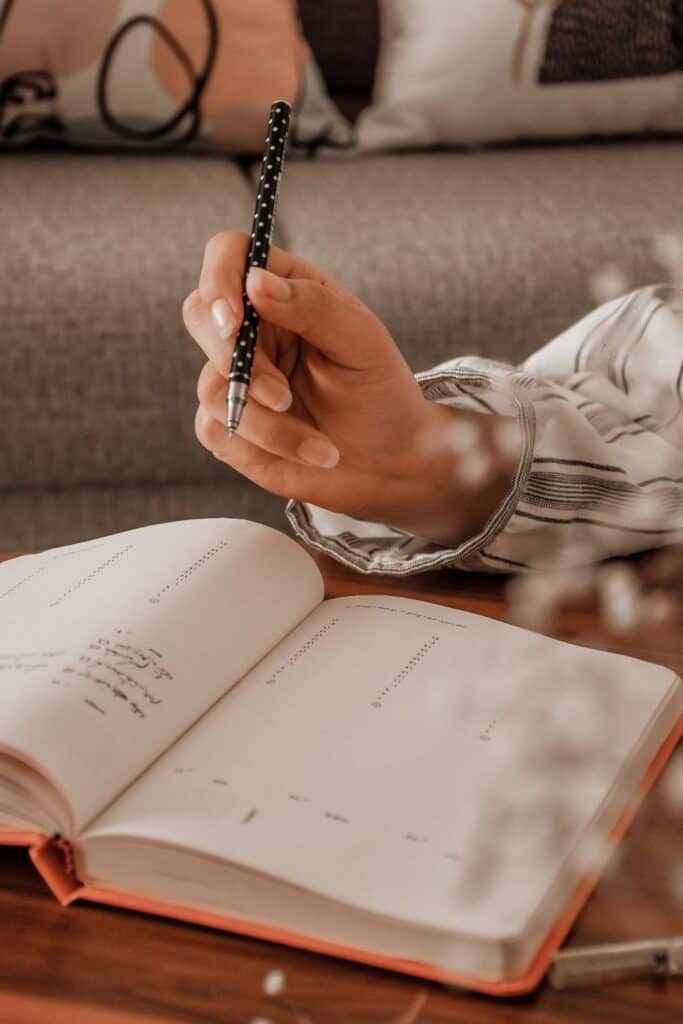 woman's hand holding a pen and writing in a planner