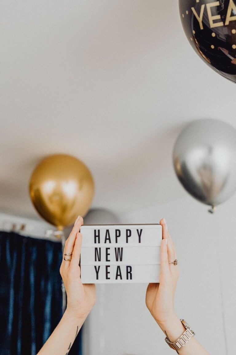 hands holding a sign that says happy new year