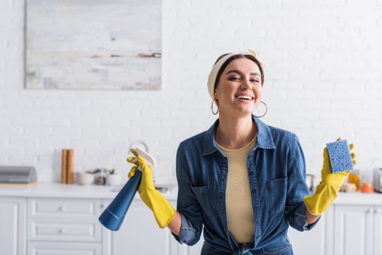woman smiling and holding cleaning supplies