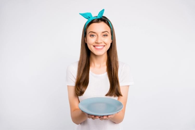 smiling woman holding up an empty plate