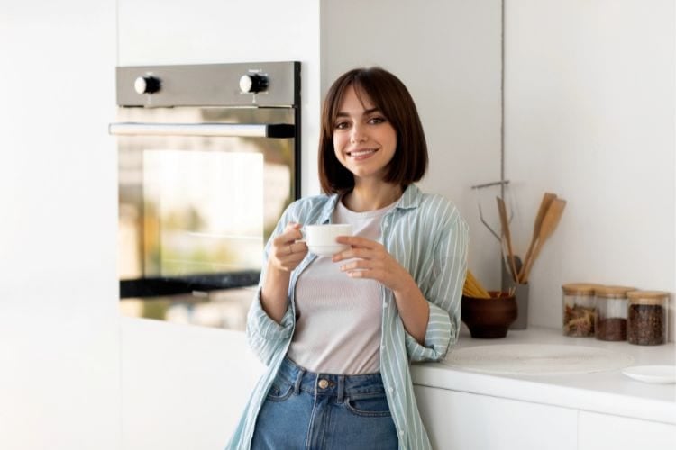 smiling woman drinking coffee in the kitchen