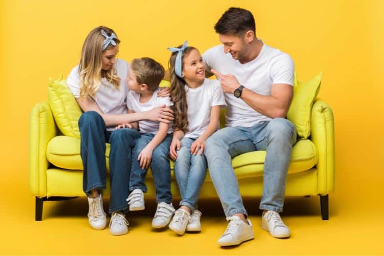 family sitting on a couch against a bright yellow background