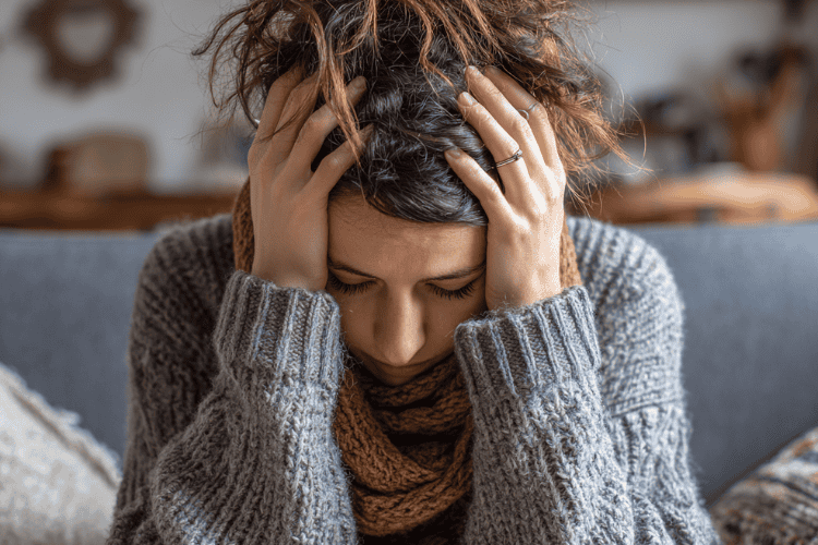 An overwhelmed mom holding her head in stress and frustration.