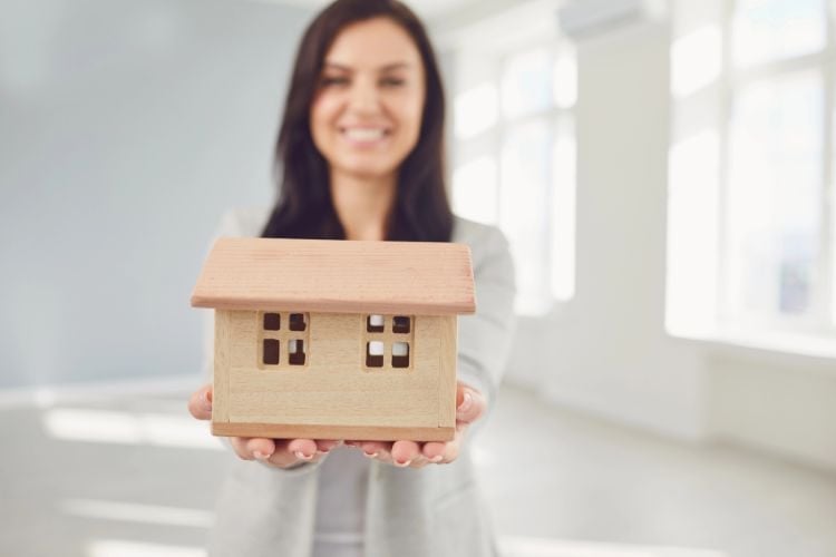 a woman holding the model of a house in her hands