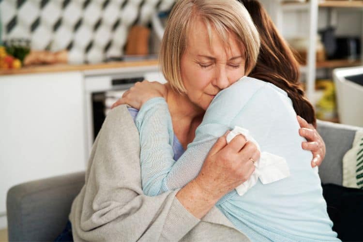 woman comforting another woman with a hug