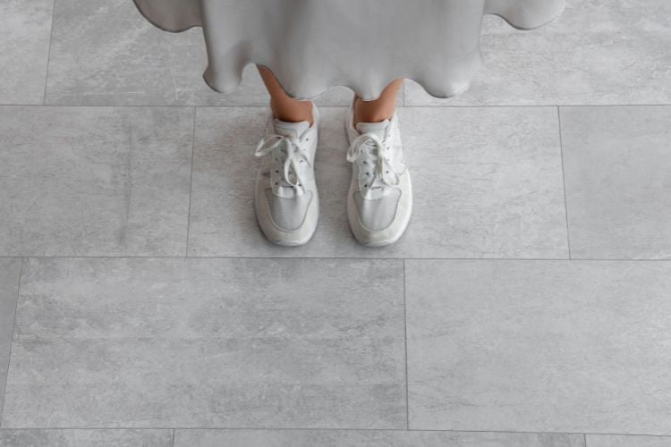 woman's tennis shoes on gray tiles